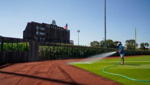 Groundskeeper Waters Grass By Wooden Scoreboard 1